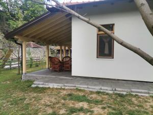 a white house with a wooden roof and a patio at Apartman Quince Gradac in Valjevo