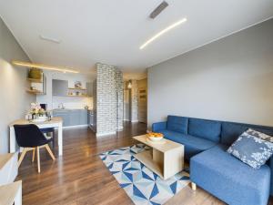 een woonkamer met een blauwe bank en een keuken bij Browar Gdański One Bedroom Apartments with Free Parking by Renters in Gdańsk