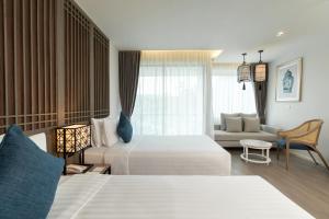 a hotel room with two beds and a couch at Bella Nara Phuket Naiyang Beach in Nai Yang Beach