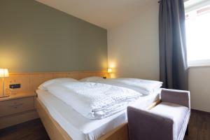 ein Schlafzimmer mit einem Bett mit einem Stuhl und einem Fenster in der Unterkunft Platterhof in Dorf Tirol