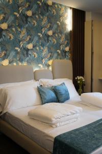 ein Bett mit blauen und weißen Kissen und einer Blumenwand in der Unterkunft Albergo Ristorante Papa in Peschiera del Garda