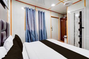 een slaapkamer met een wit bed en blauwe gordijnen bij OYO Jai Santoshi Dhaam in Vrindāvan