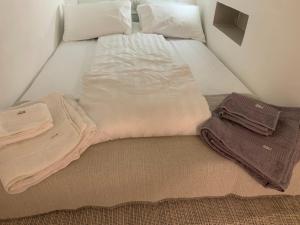 ein Bett mit weißer Bettwäsche und Handtüchern darauf in der Unterkunft Il Piccolo Giustiniani 20 in Genua