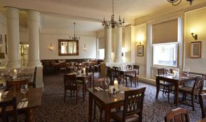 un ristorante con tavoli e sedie in una stanza di George Hotel by Greene King Inns a Huntingdon