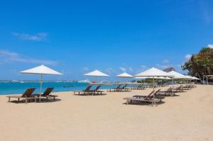 un gruppo di sedie e ombrelloni in spiaggia di Mercure Resort Sanur a Sanur