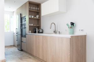 a kitchen with wooden cabinets and a stainless steel refrigerator at AB Properties - Chic House Marbella - 3 mm to Puerto Banús and Beach - Golden Mile - Direct access to Pool and Tropical Garden in Marbella