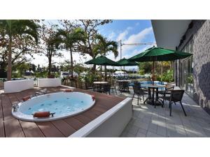 Green Rich Hotel Okinawa Nago - Vacation STAY 49889v في ناغُو: يوجد حوض استحمام ساخن على السطح مع طاولة وكراسي