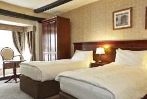 una camera d'albergo con due letti e una finestra di George Hotel by Greene King Inns a Huntingdon
