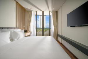 een slaapkamer met een groot bed en een flatscreen-tv bij Tashi Ocean Hotel & Apartment Da Nang in Da Nang