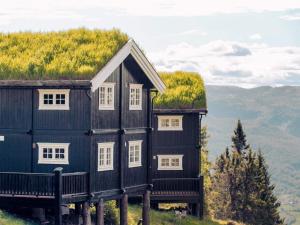 a black house with a grass roof on a hill at 10 person holiday home in Fåvang in Strande +3 photos