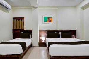 two beds in a room with white walls at OYO Hotel HILL PARK I in Vadodara