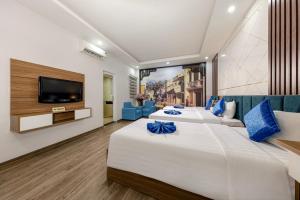 a hotel room with two beds and a flat screen tv at Aquarius Grand Hotel in Hanoi