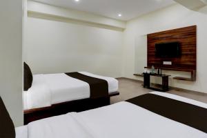 a hotel room with two beds and a flat screen tv at OYO Hotel HILL PARK I in Vadodara