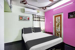 1 dormitorio con 1 cama con paredes de color rosa en OYO SS Home Stay - An Unique Home Stay, en Tirupati