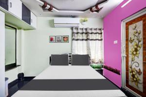 OYO SS Home Stay - An Unique Home Stay في تيروباتي: غرفة بها سرير وبجدران وردية وبيضاء