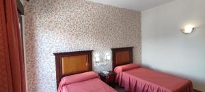 Habitación con 2 camas y sábanas rosas. en Hotel El Doncel, en Atarfe
