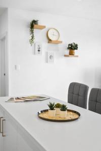 a white counter with two chairs and a table with plants on it at Lightview Oasis- Modern 2BR Apt- WiFi & Parking in Broadview