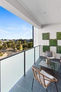 an apartment balcony with a glass table and chairs at Lightview Oasis- Modern 2BR Apt- WiFi & Parking in Broadview