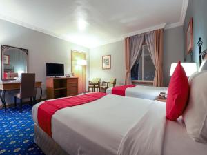 a hotel room with two beds and a desk at City Plaza Hotel in Fujairah