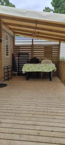 a patio with awning and a bench on a deck at Mobil Home 3 chambres in Ouistreham