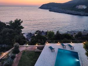 einen Pool mit Stühlen und Blick auf das Wasser in der Unterkunft Sunset Villa Montenegro in Radovanići