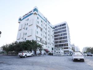 un edificio blanco con coches estacionados en un estacionamiento en City Plaza Hotel en Fujairah