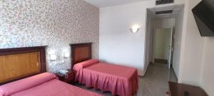 Habitación con 2 camas y sábanas rosas. en Hotel El Doncel en Atarfe