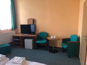 a room with a desk and chairs and a television at Grandhotel Nový Bor in Nový Bor