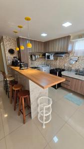 uma cozinha com um balcão de madeira com bancos em Apartamento Confortável - Porto das Dunas - Perto do Beach Park em Aquiraz