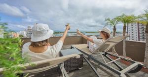 two women sitting in chairs on a balcony drinking coffee at Ishigakijima Hotel Cucule in Ishigaki Island