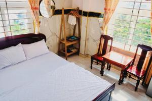 a bedroom with a bed and two chairs and windows at Hoa Bien Motel in Ly Son