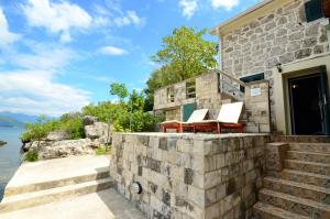 een stenen huis met 2 stoelen en een tafel bij Holiday Home Brinic in Tivat