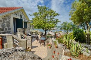 a house with a patio with chairs and flowers at Holiday Home Brinic in Tivat
