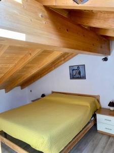 a yellow bed in a room with wooden ceilings at Ruti's House in Cassano Magnago