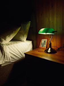 una lámpara verde sobre una mesa de madera junto a una cama en Rino hauss, en Fındıklı