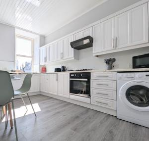 a kitchen with white cabinets and a washer and dryer at Campbeltown Central in Campbeltown