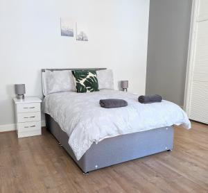 a white bedroom with a bed and a night stand at Campbeltown Central in Campbeltown