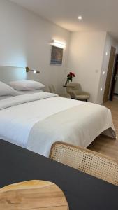 een slaapkamer met een groot wit bed en een stoel bij Le cap dagde in Cap d'Agde