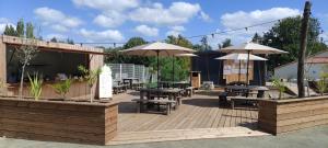 a wooden deck with tables and umbrellas at Camping Onlycamp Le Petit Bocage in Les Essarts