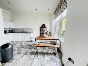cocina con armarios blancos y mesa de madera en Leah Suite by Koya Homes en Barry