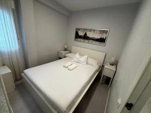 - une petite chambre avec un lit blanc et 2 tables dans l'établissement Manero Molla (Centro Alicante), à Alicante