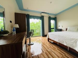 a bedroom with a bed and a desk with a fan at Phong Nha Moonlight Villas in Phong Nha