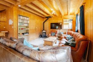 a living room with a leather couch and a tv at Chalet Etoile in Saint-Jean-d'Aulps