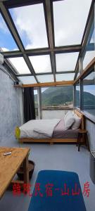 1 dormitorio con cama, mesa y ventanas en Yardbnb 2F, en Jiufen