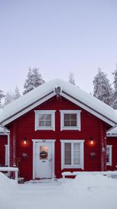 a red house with a snow covered roof at Kotatuli Forest Lodge in Rovaniemi