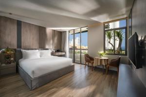 a hotel room with a bed and a large window at Tashi Ocean Hotel & Apartment Da Nang in Da Nang