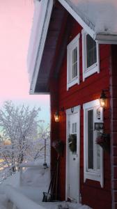 une maison rouge avec une porte blanche et des fenêtres dans l'établissement Kotatuli Forest Lodge, à Rovaniemi