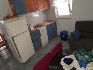 Elle comprend une petite cuisine équipée d'un réfrigérateur blanc et de placards bleus. dans l'établissement Gordana Apartments, à Fažana