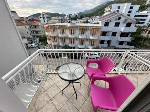 einen Balkon mit rosa Stühlen und einem Tisch auf dem Balkon in der Unterkunft Apartmani Vukcevic in Rafailovici