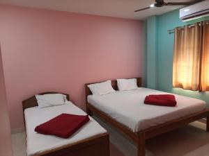 two beds in a room with two red towels on them at hotel sudhara in Tirukkadaiyūr